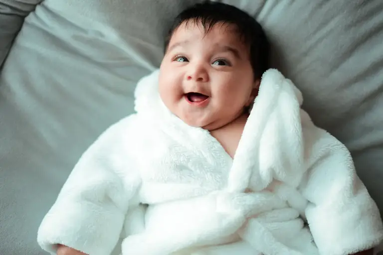 Bebé sonriendo envuelto en una manta blanca